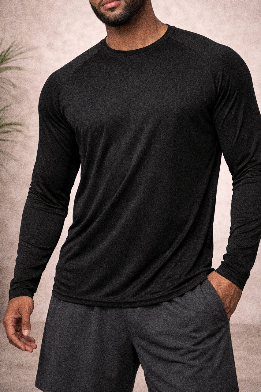 Man wearing a black long-sleeve shirt and gray pants against a neutral background